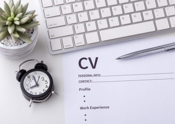 CV with pen, computer keyboard and clock on white desk