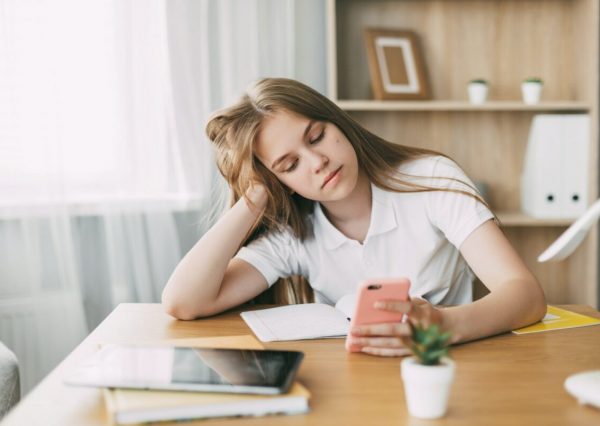 cute-schoolgirl-is-tired-of-doing-homework-and-is-looking-for-a-solution-to-the-problem-online-e1647698214435